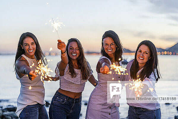 Happy women having fun with sparklers at beach