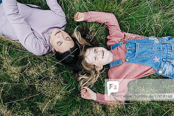 Smiling mother lying with daughter on grass