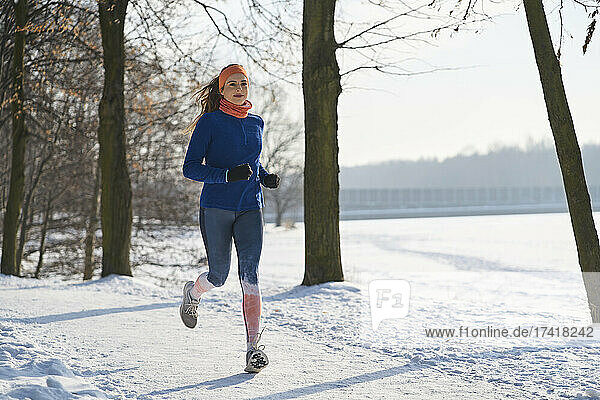 Young woman jogging on snow during winter