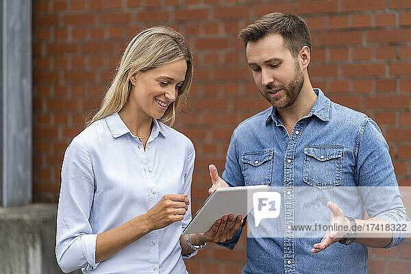 Business professional team using digital tablet in front of wall