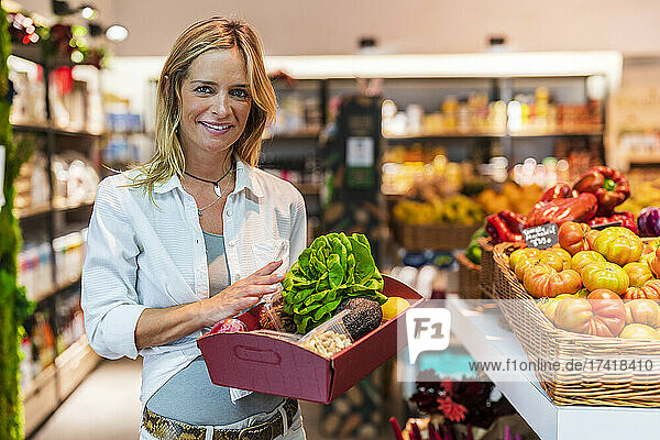 Woman carrying groceries tray at organic store