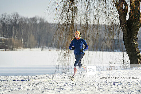Woman running on snow during sunny day
