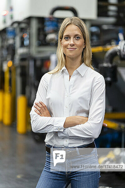 Female professional with arms crossed standing at factory