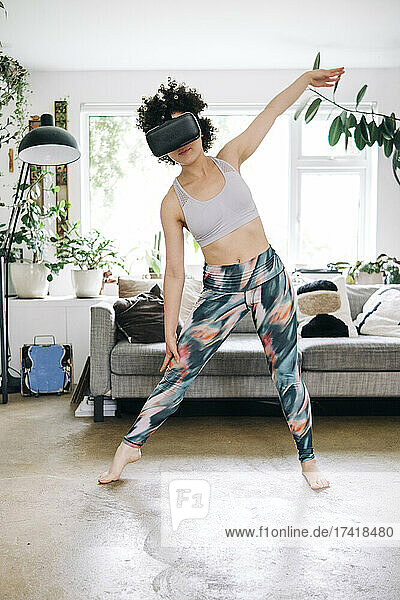 Woman using virtual reality headset while exercising in living room
