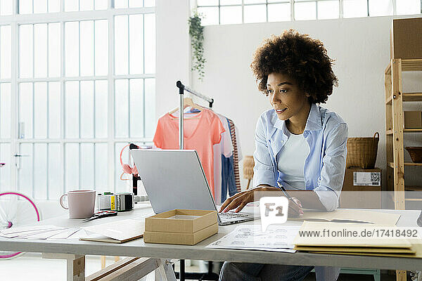 Female fashion designer working on laptop in studio