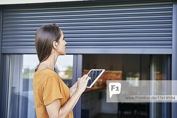 Woman controlling blinds through digital tablet