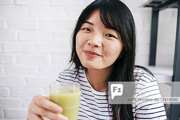 Young woman holding healthy smoothie at home