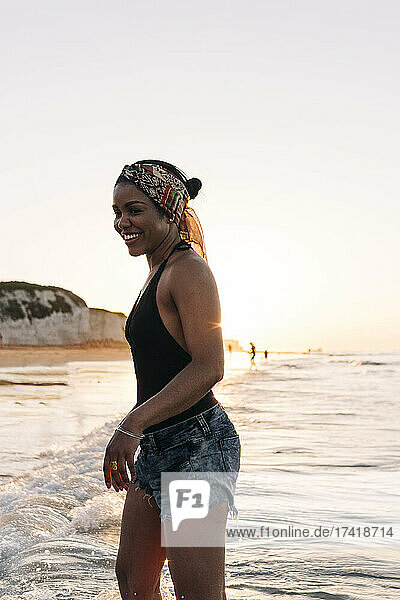 Lächelnde Frau  die sich bei Sonnenuntergang am Strand amüsiert