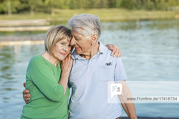 Senior woman leaning on man shoulder at lake