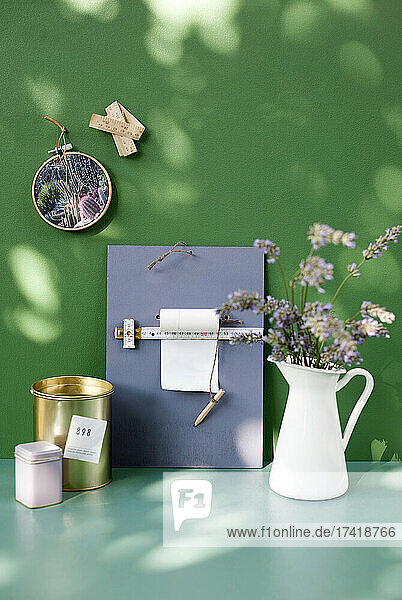 Flower jug and clipboard on table