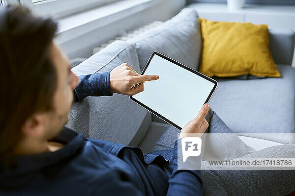 Businessman using digital tablet while sitting on sofa at office