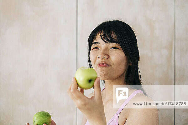 Young woman eating apple at home