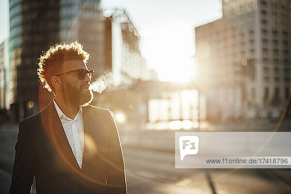 Male freelancer wearing sunglasses standing on street
