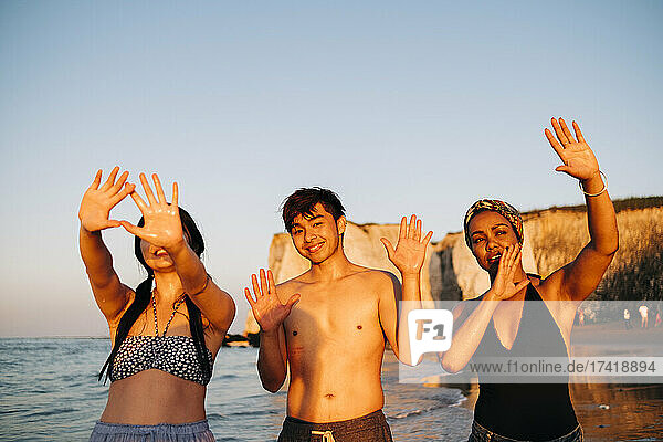 Male and female friends gesturing at beach