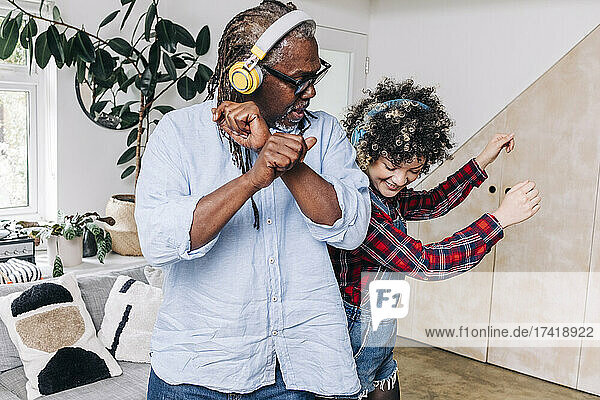 Father and daughter with headphones dancing together at home