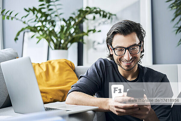 Male freelance worker using smart phone while working at home