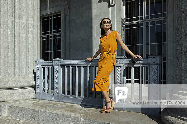 Junge Frau schaut weg  während sie an einem sonnigen Tag vor dem Tor der National Gallery Singapore steht