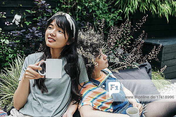 Junge Freunde entspannen sich mit Kaffeetassen auf einem Sitzsack im Hinterhof
