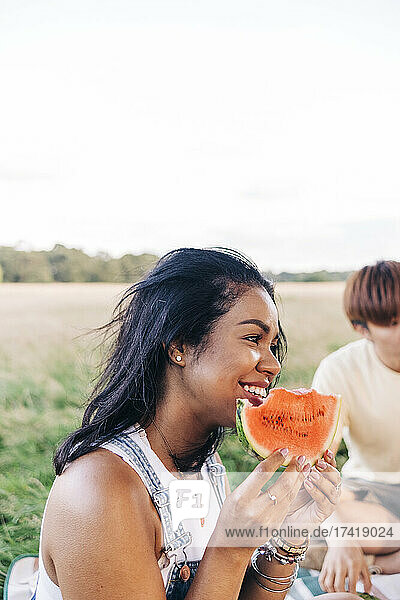 Smiling woman holding watermelon slice during picnic at park
