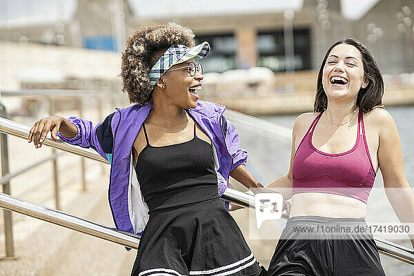 Frauen mittleren Alters lachen  während sie vor dem Geländer stehen