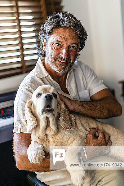 Man holding dog while sitting at home
