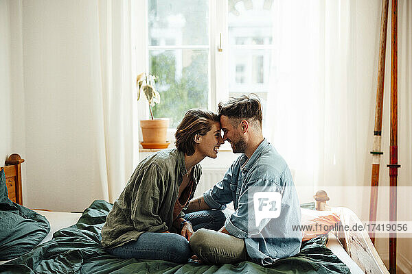 Paar berührt die Stirn  während es zu Hause im Bett sitzt