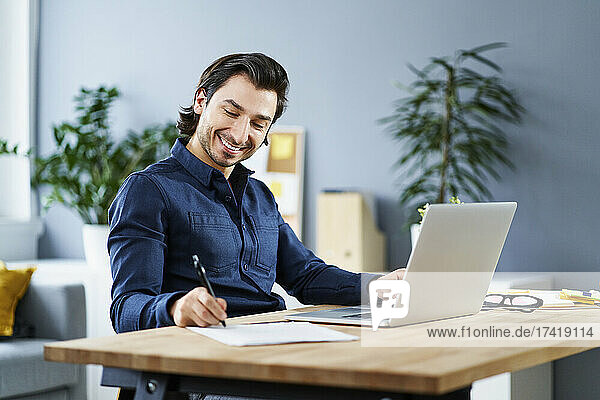 Smiling businessman signing contract at desk