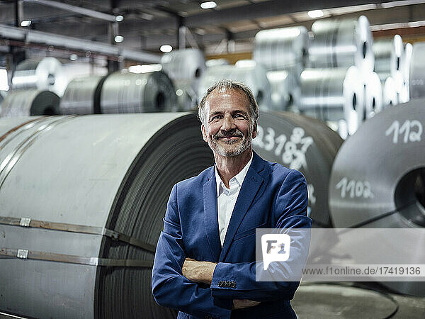 Smiling male professional with arms crossed standing at warehouse