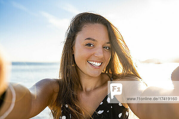 Happy beautiful woman taking selfie at beach