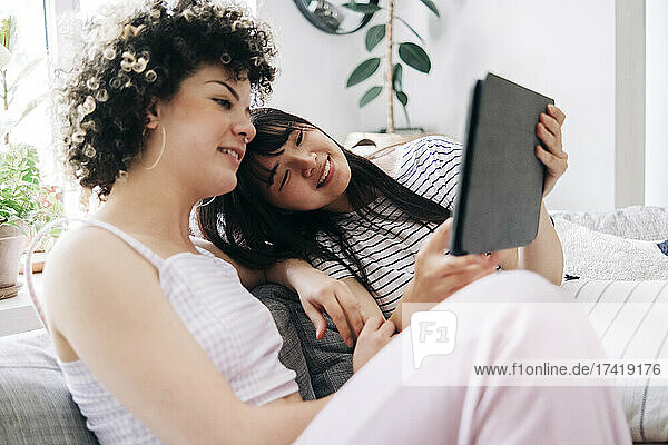 Female friends sharing digital tablet while sitting in living room