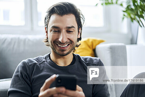 Happy man using smart phone at home