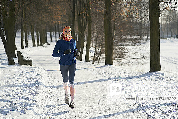 Lächelnde Frau läuft im Winter auf Schnee