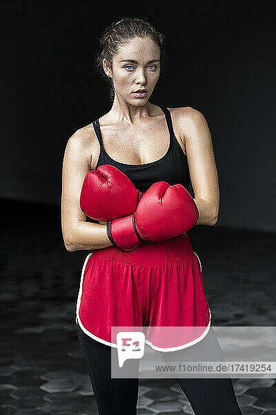 Female boxer with arms crossed standing at basement