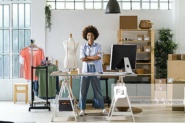 Confident female fashion designer with arms crossed standing at studio