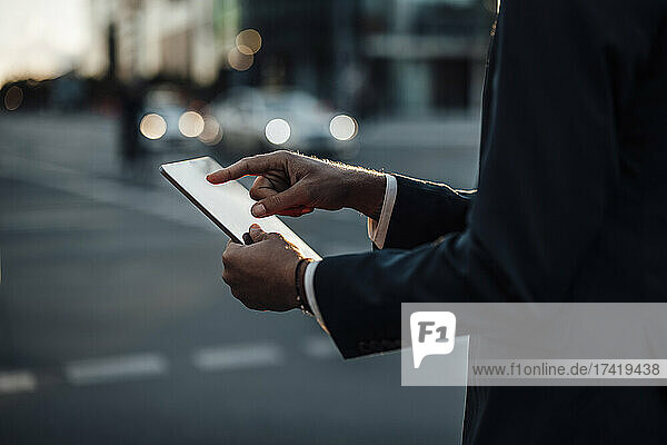 Male freelancer using digital tablet on street