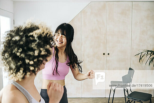 Smiling woman practicing zumba with friend at home