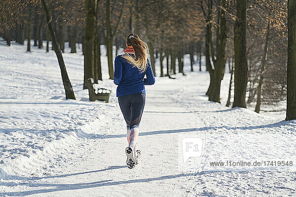 Woman jogging on footpath during snow in winter