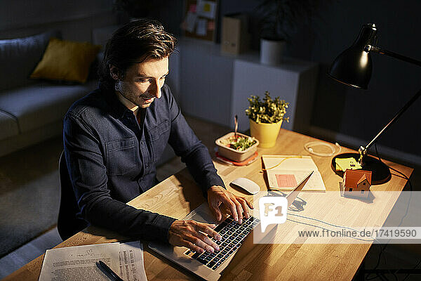 Male freelance worker working late night at home office