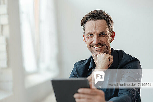 Smiling male professional holding digital tablet at work place