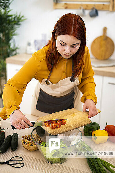 Woman with cutting board preparing food at table in kitchen