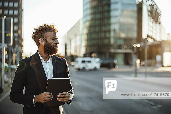 Mature businessman holding digital tablet on street