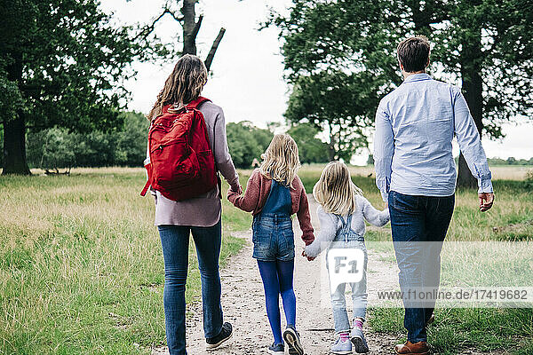 Family holding hands while walking together at park