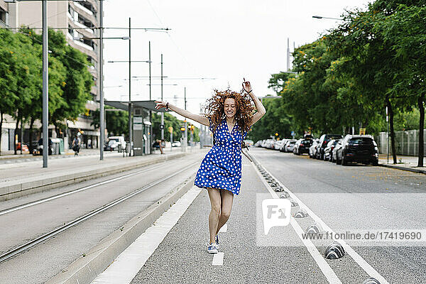 Carefree woman dancing on road