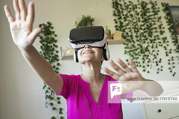 Woman gesturing while enjoying virtual reality through headset at home