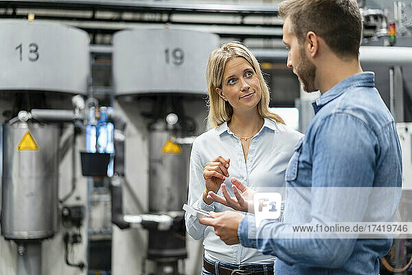 Female business professional listening to male colleague in factory