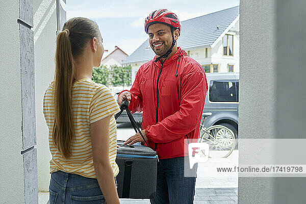 Female customer receiving order from delivery person at doorway