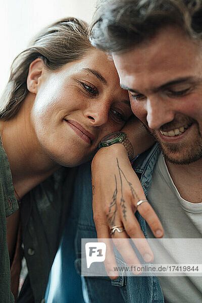 Smiling woman leaning on boyfriend shoulder at home