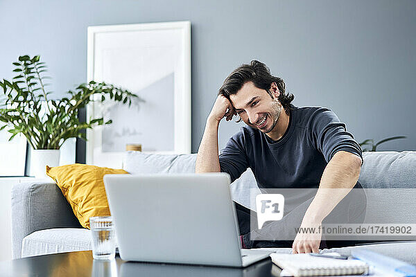 Businessman with head in hand looking at laptop while sitting on sofa
