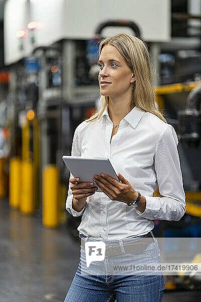 Female business professional with digital tablet at factory