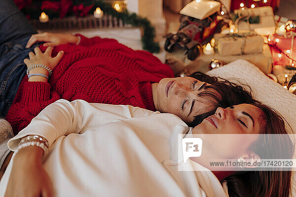 Young women with eyes closed relaxing at home during Christmas
